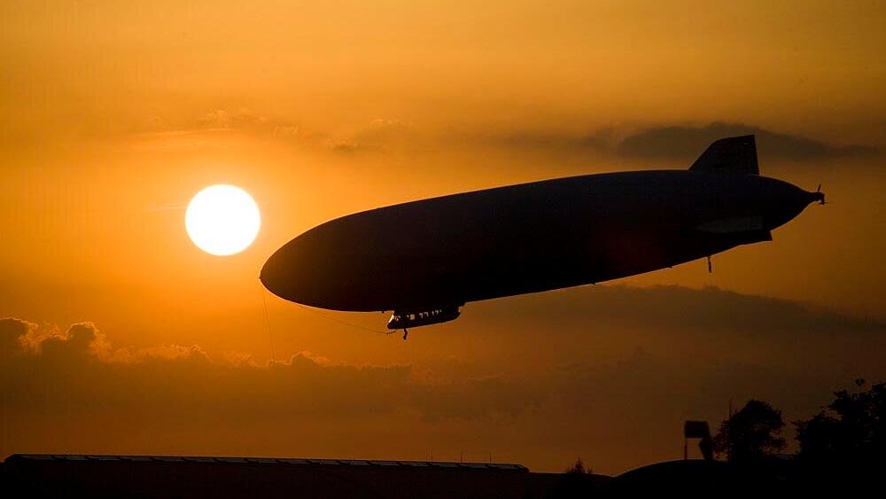 Zeppelin am Abendhimmel über dem Bodensee mit orangener Sonne