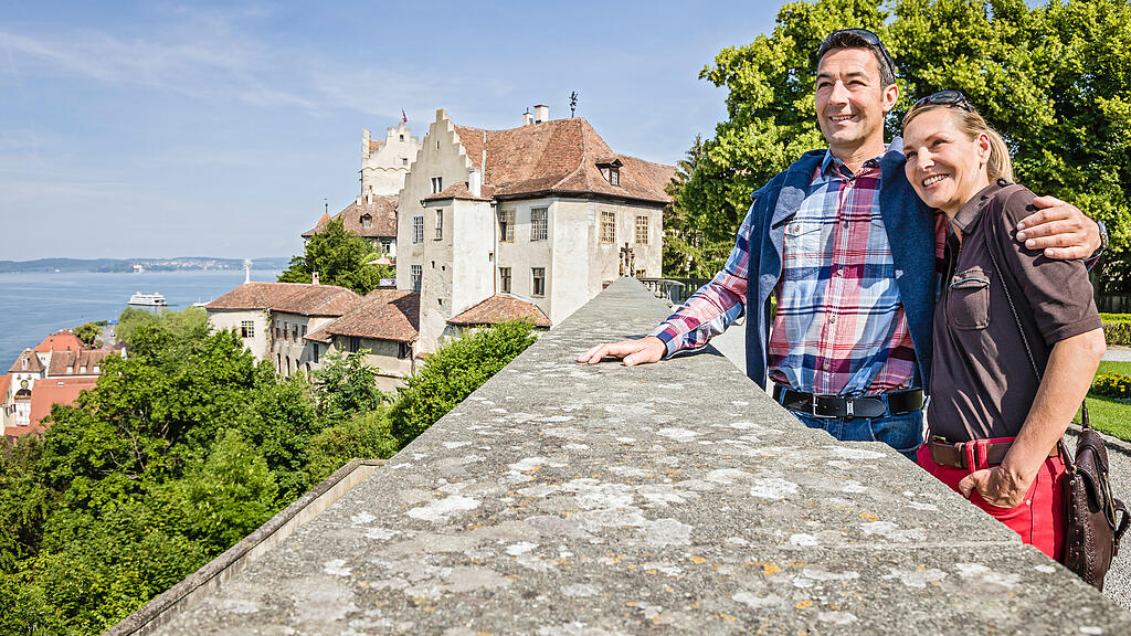 Paar umarmt sich und genießt die Aussicht im Garten der Burg Meersburg Paar umarmt sich und genießt die Aussicht im Garten der Burg Meersburg