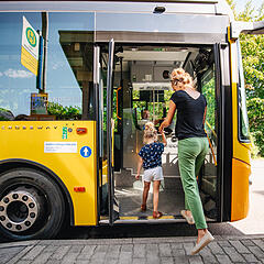 Mutter und Kind steigen in den gelben Bus auf der Halbinsel Höri