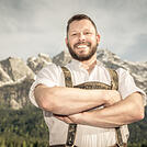 Portrait bayrischer Mann in Tracht in den Bergen