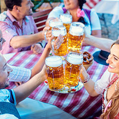Besucher eines Oktoberfests beim Anstoßen mit Bierkrügen Besucher eines Oktoberfests beim Anstoßen mit Bierkrügen