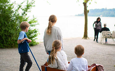 Mainau-Entdeckungsreise Familie gehen mit Bollerwagen auf der Insel Mainau auf Entdeckungsreise