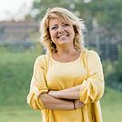 Lächelnde Frau im gelben Kleid draußen im Grünen Jessica