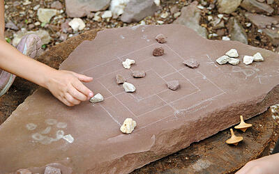 Kinder spielen ein auf Stein aufgemaltes Brettspiel