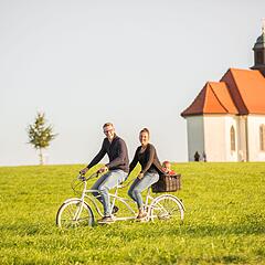 Fahrradfahrer im Friedrichshafener Umland mit Kirche im Hintergrund