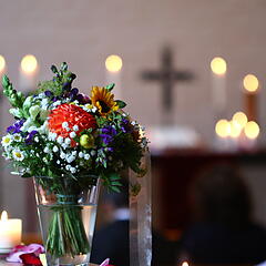Blumenstrauß in einer Kirche mit Kreuz und Kerzen im Hintergrund
