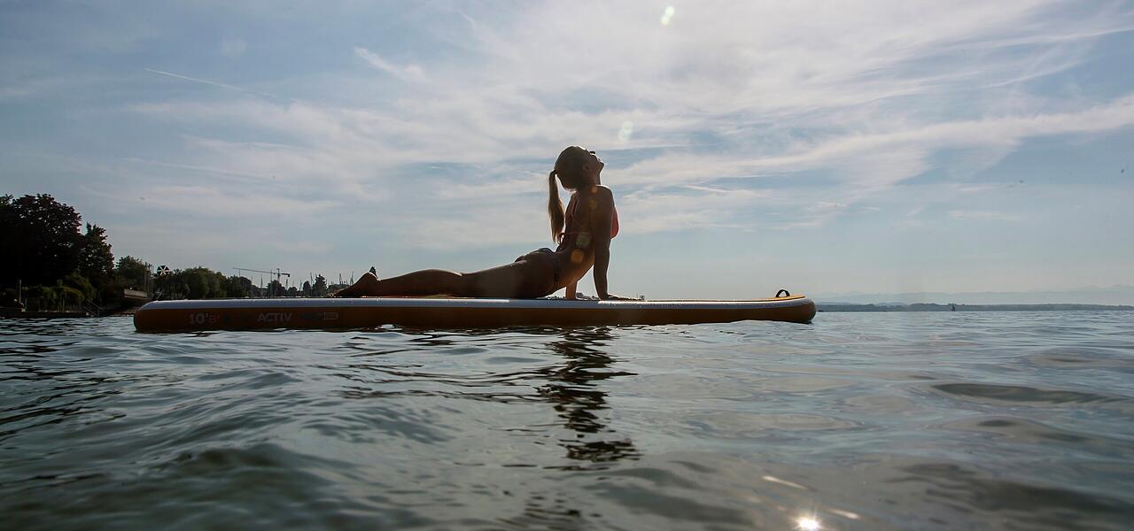 Frau sonnt sich auf einem SUP in der Sonne bei Friedrichshafen