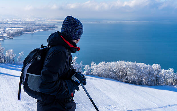 Mann beim Winterwandern in Vorarlberg genießt Aussicht auf den Bodensee