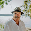 Älterer, lächelnder Herr mit Hemd und Hut am Ufer des Bodensees