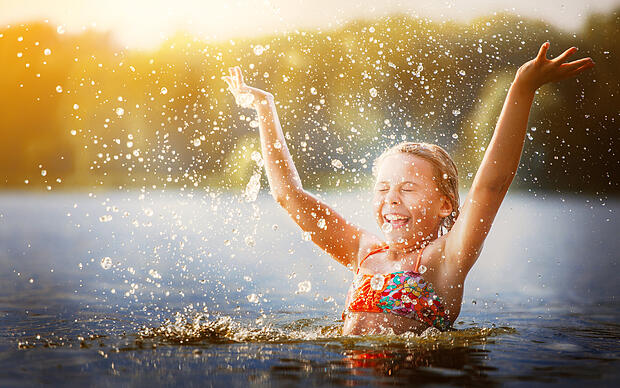 Kleines Mädchen glücklich im Wasser spielend