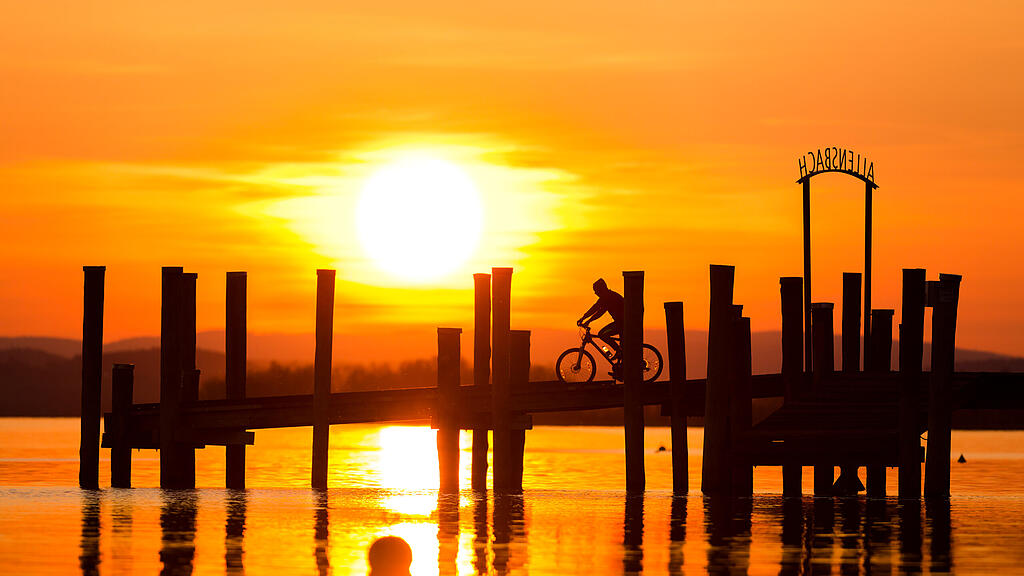 Fahrradfahrer auf dem Steg in Allensbach bei Sonnenuntergang
