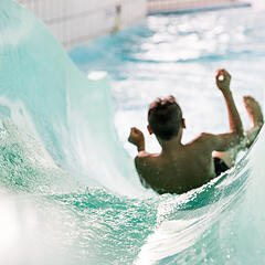 Junge rutscht von einer Rutsche im Schwimmbad