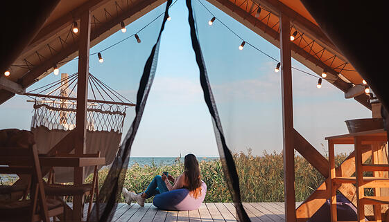 Beautiful young girl in nature by the lake. woman resting in glamping in a picturesque place far from the city. self-isolation leave without people