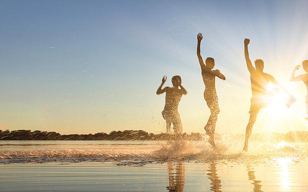 Junge Menschen rennen bei Sonnenschein in den See